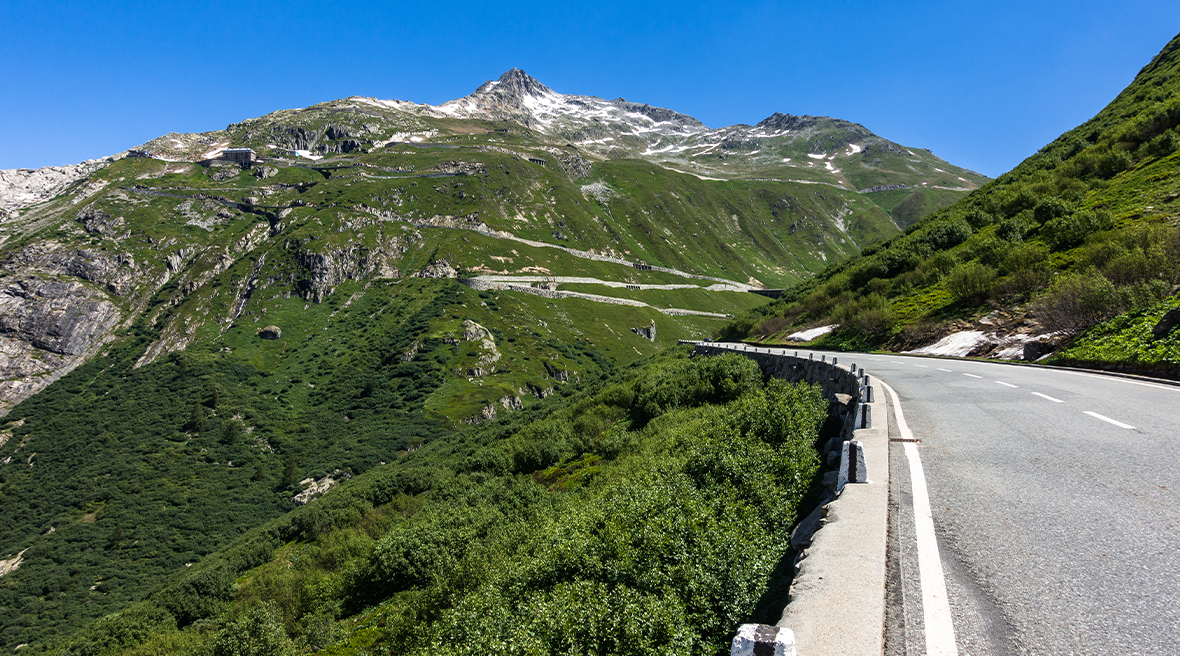 Furka pass road within the Swiss Alps surrounded by stunning greenery